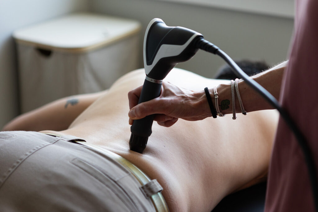 Therapist using therapy device on patient’s lower back