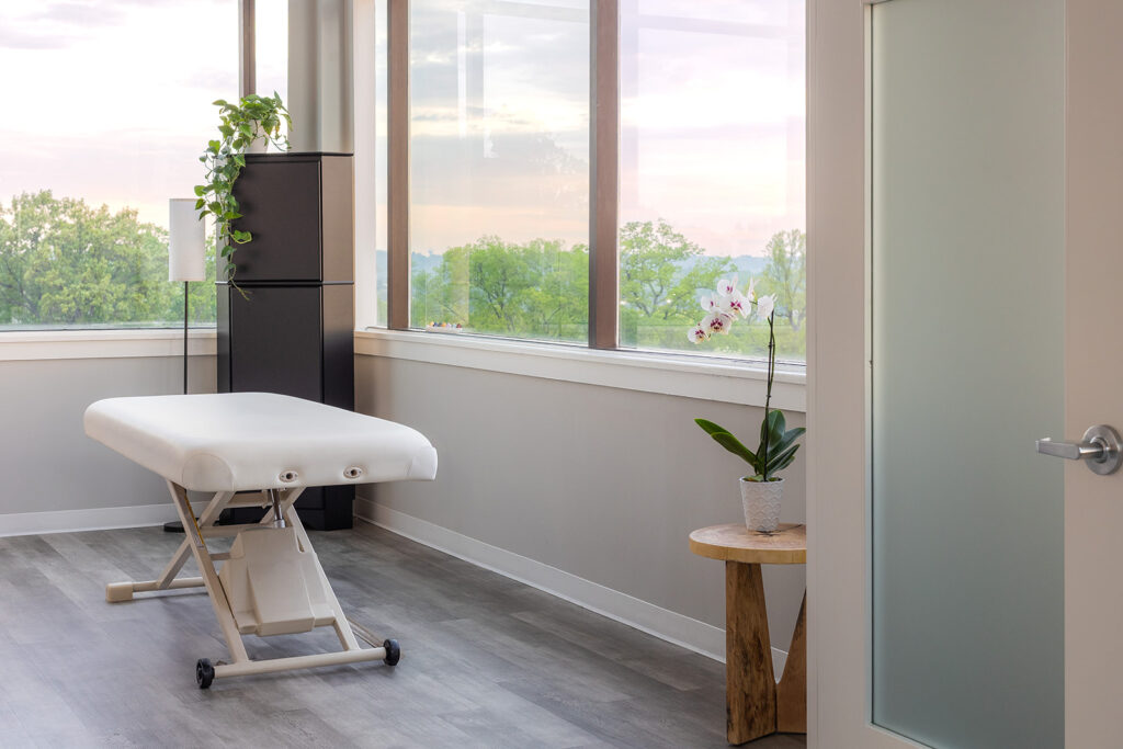 Modern treatment room with large window and therapy table